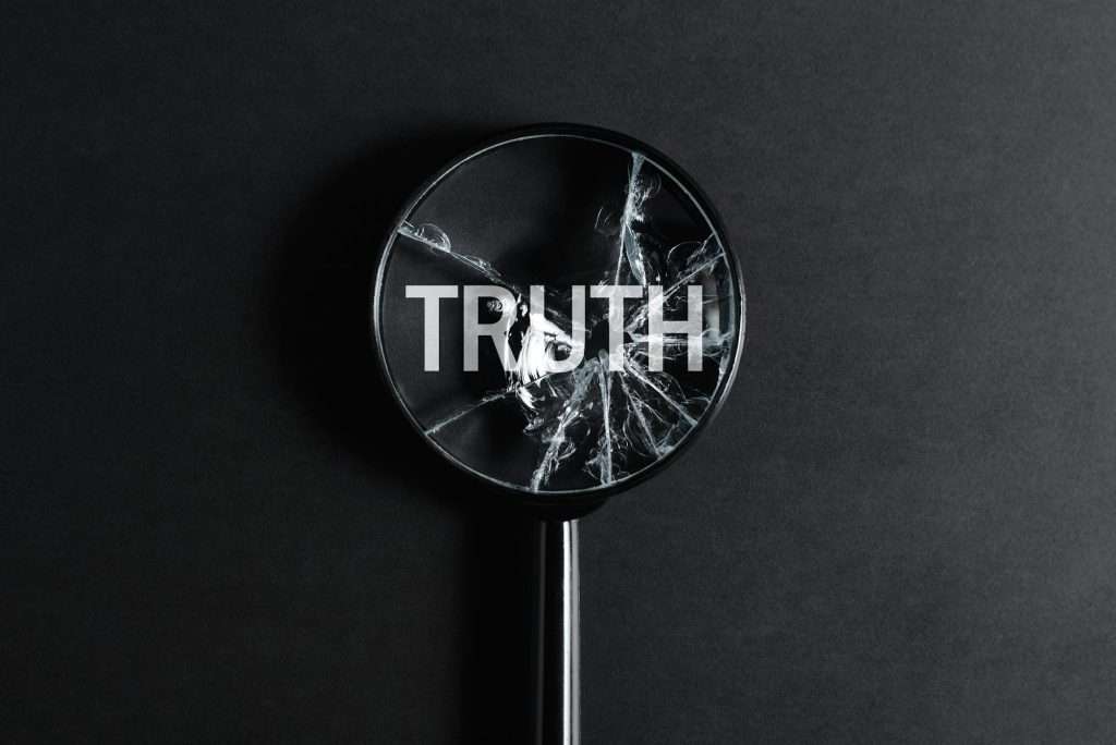 Broken magnifying glass focused on word Truth on black background, top view. Creative concept