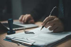 Businessperson hand holding pen signature document