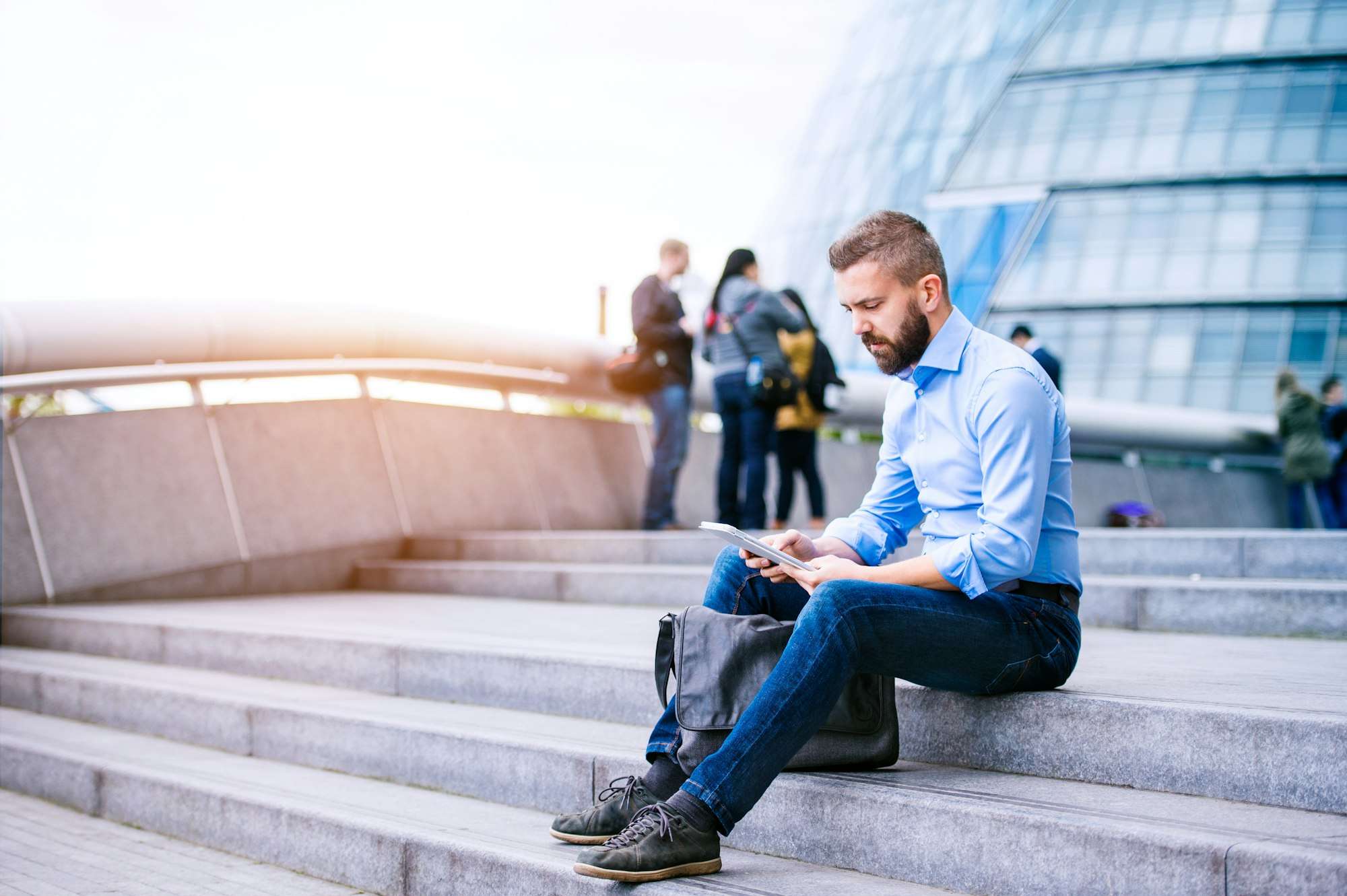 Manager with tablet, sitting on stairs, London, City Hall