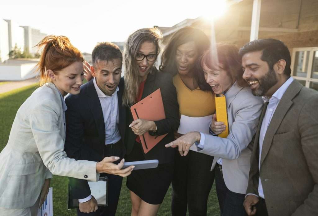 Multiracial group of business people gossiping looking at cellphone