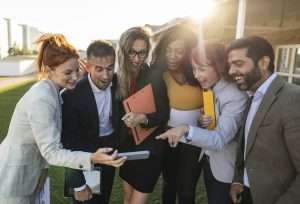 Multiracial group of business people gossiping looking at cellphone