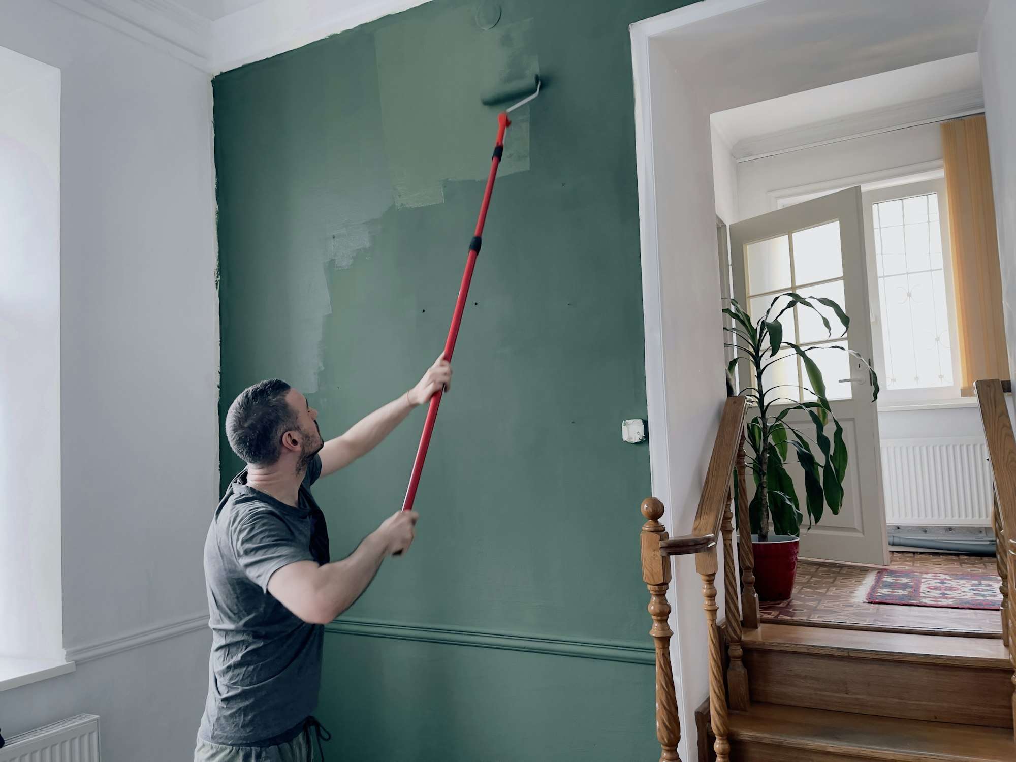 Spring mood home improvement. Green wall. Working man