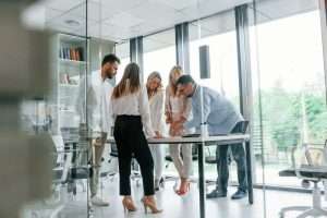 Standing by the table near big windows. Group of professional business people is in the office