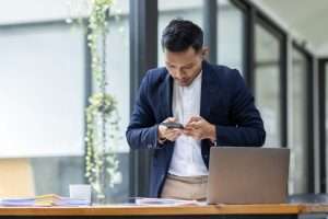 Take picture, Asian Businessman sitting at workplace desk and Taking Photograph Of Document In Offic