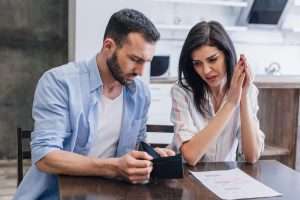 Upset bankrupts with empty purse at table with document in room