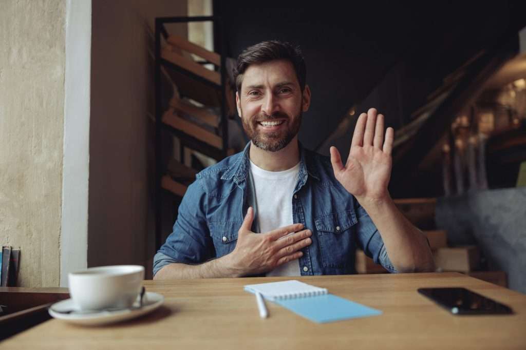 Young handsome man with hand on chest, making oath promise gesture in cafe. Promissing concept
