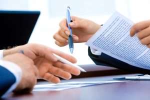 Two people signing a contract representing the legal remedies available for breach of contract in Canadian law