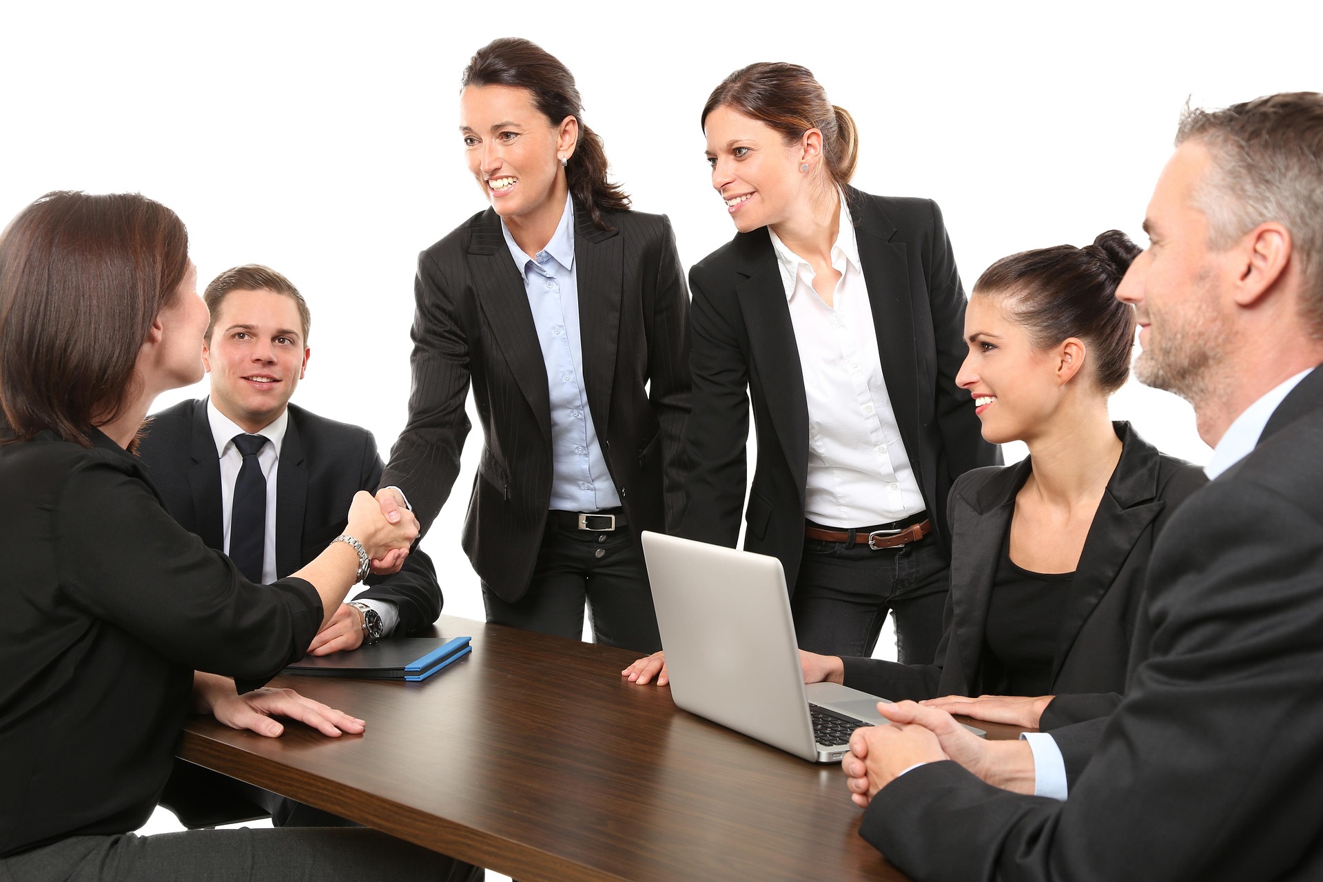 Business people shaking hands across a table at a meeting, representing the moment in M&A negotiations when a handshake or preliminary agreement may create binding legal obligations before the definitive contract is signed