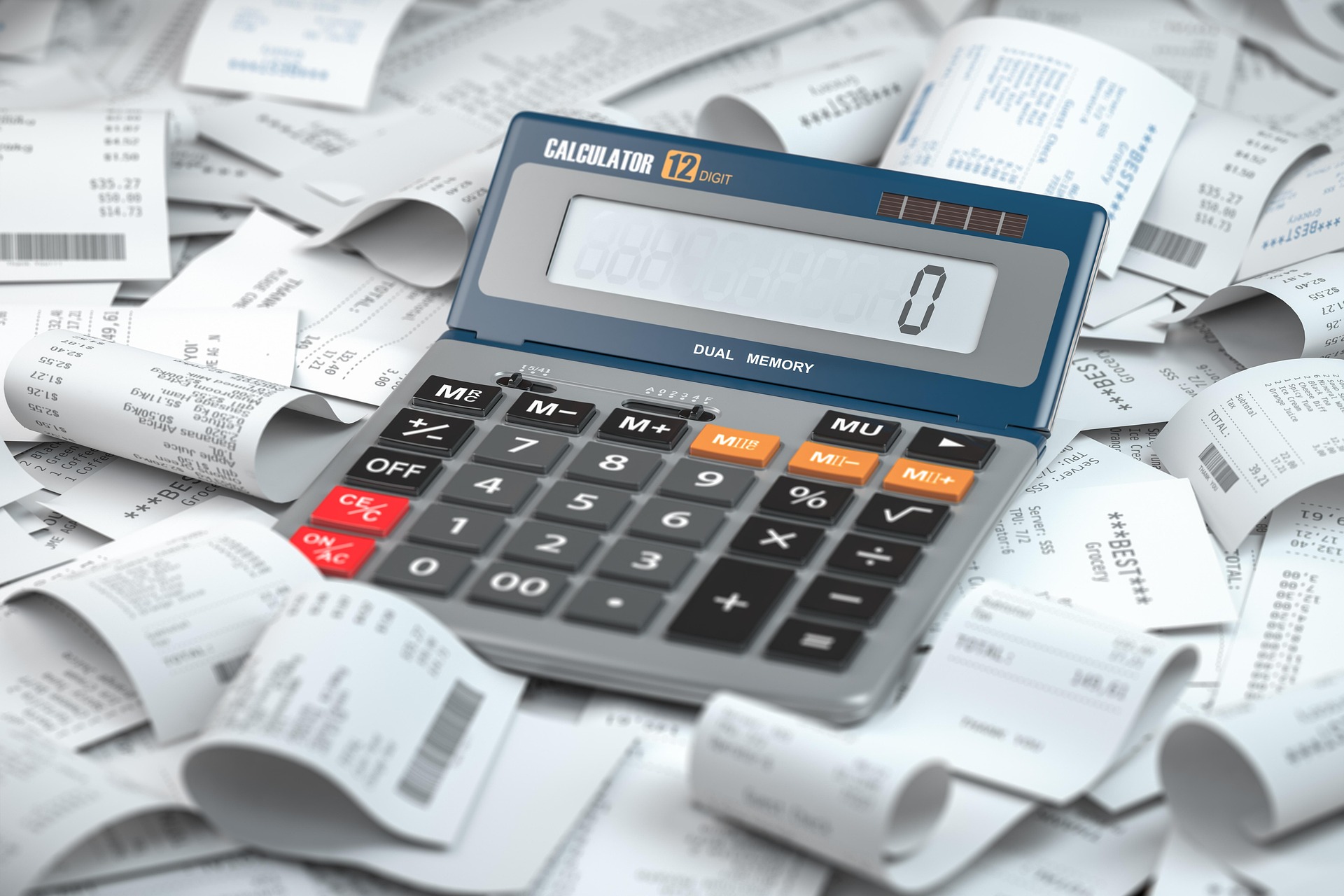A calculator beside a pile of receipts