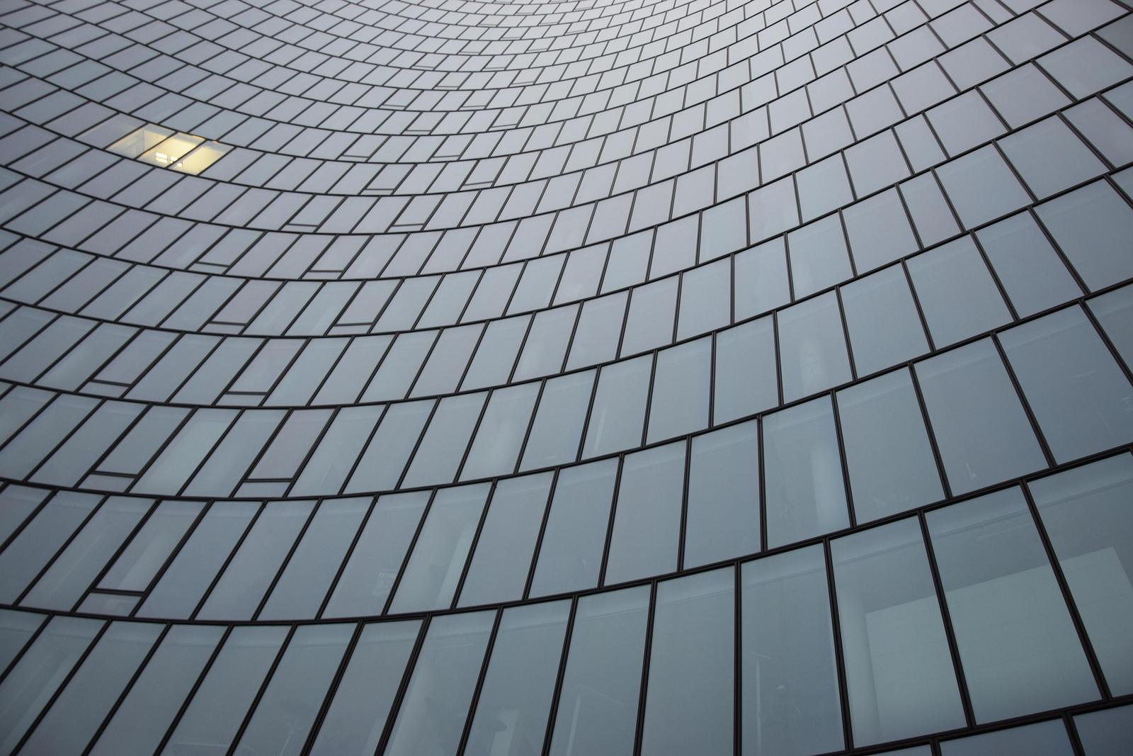 Curved glass facade of an office tower, in black and white